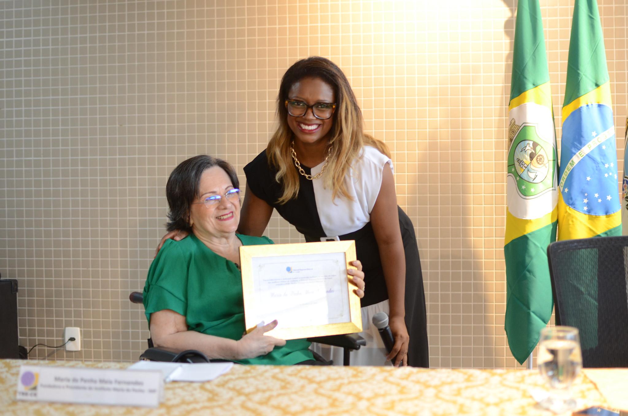 Maria da Penha recebe homenagem das mãos da juíza Bruna Rodrigues