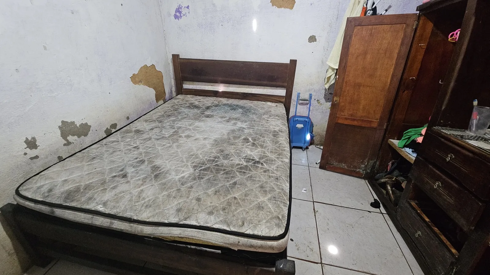 Colchão ensopado e guarda-roupas com base desmanchada são lembretes diários do impacto das chuvas à casa de Emanoela
