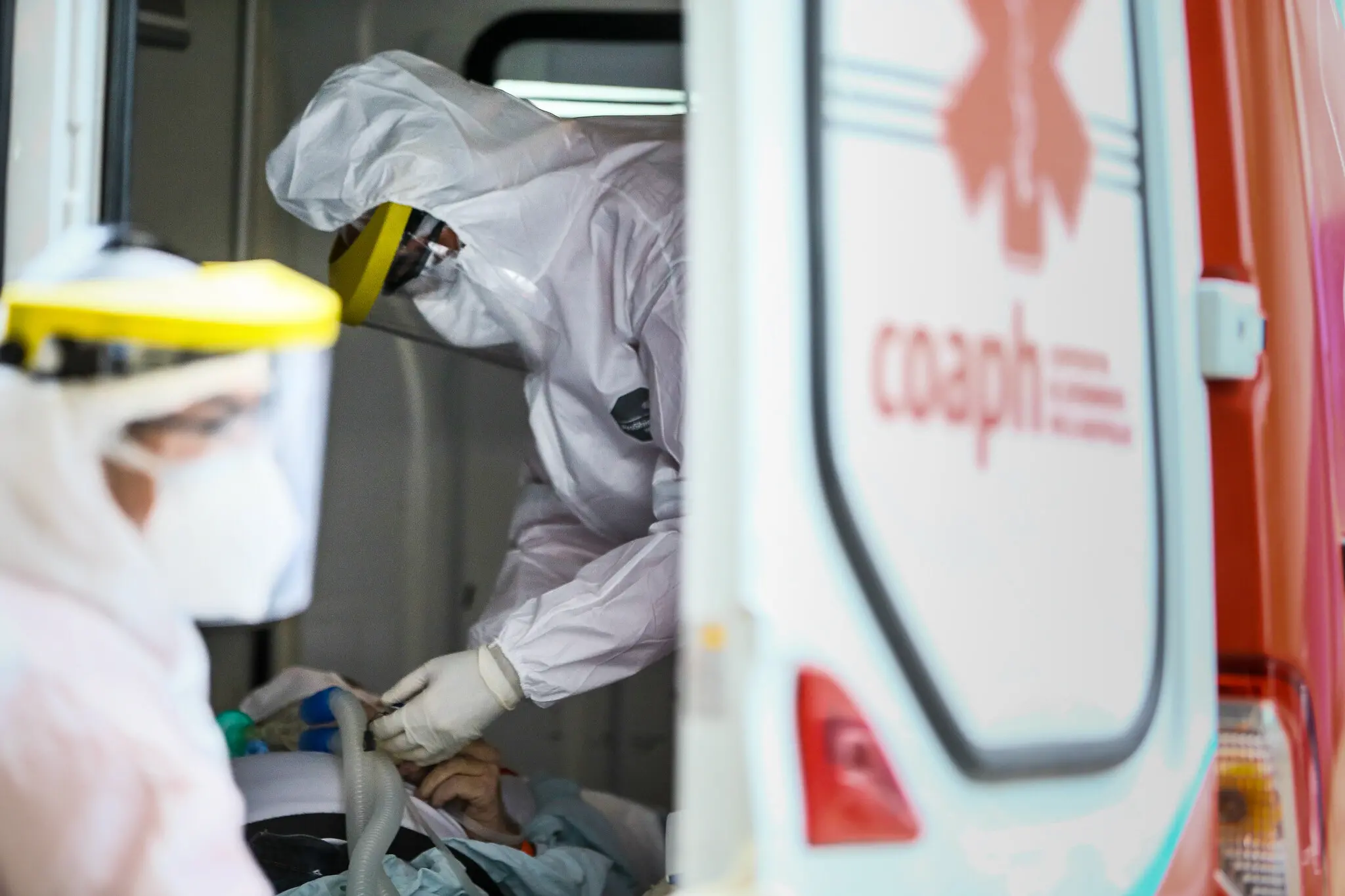 Profissionais da saúde em ambulância, usando roupa especial para evitar contágio