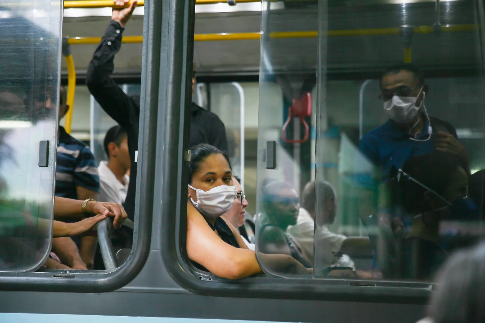 Pessoas em ônibus de Fortaleza, de máscara, olhando para a câmera