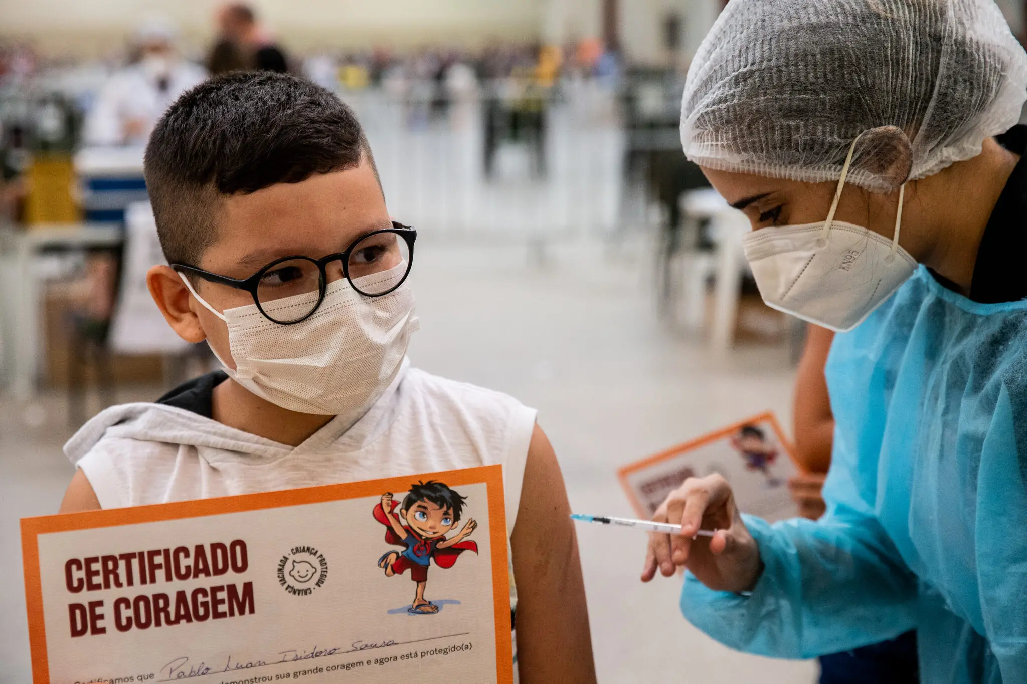 Criança sendo vacinada e segurando o 