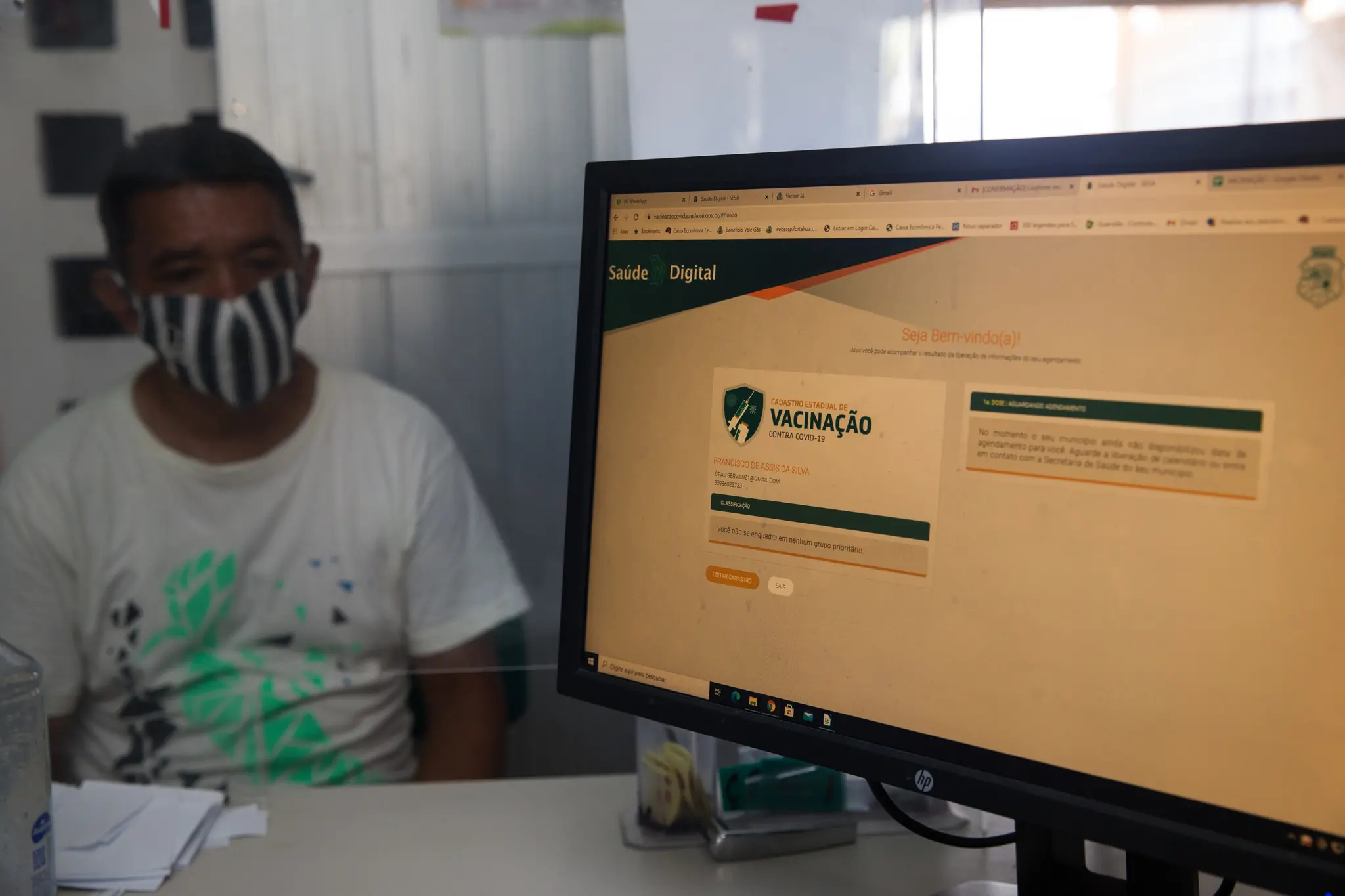 Paciente em unidade de saúde. Na frente dele aparece uma tela do site Saúde Digital