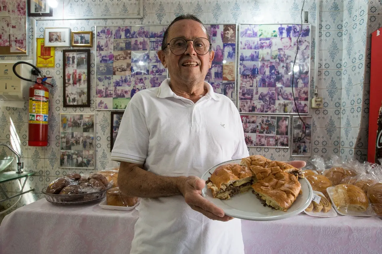 Homem mostra sanduíche de carne e queijo