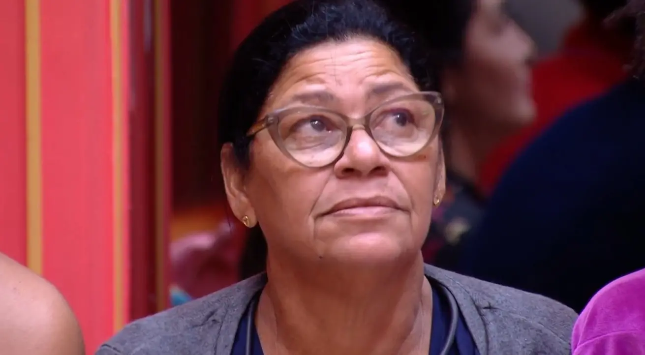 Joselma é uma mulher idosa que usa óculos de grau. Seu cabelo é preto e está amarrado em um rabo de cavalo