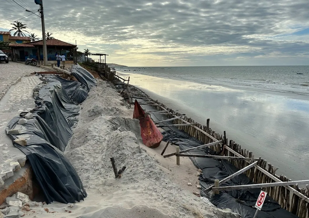 Visão em nível de solo da faixa de praia, com estruturas de contenção do avanço do mar em evidência na Praia de Peroba