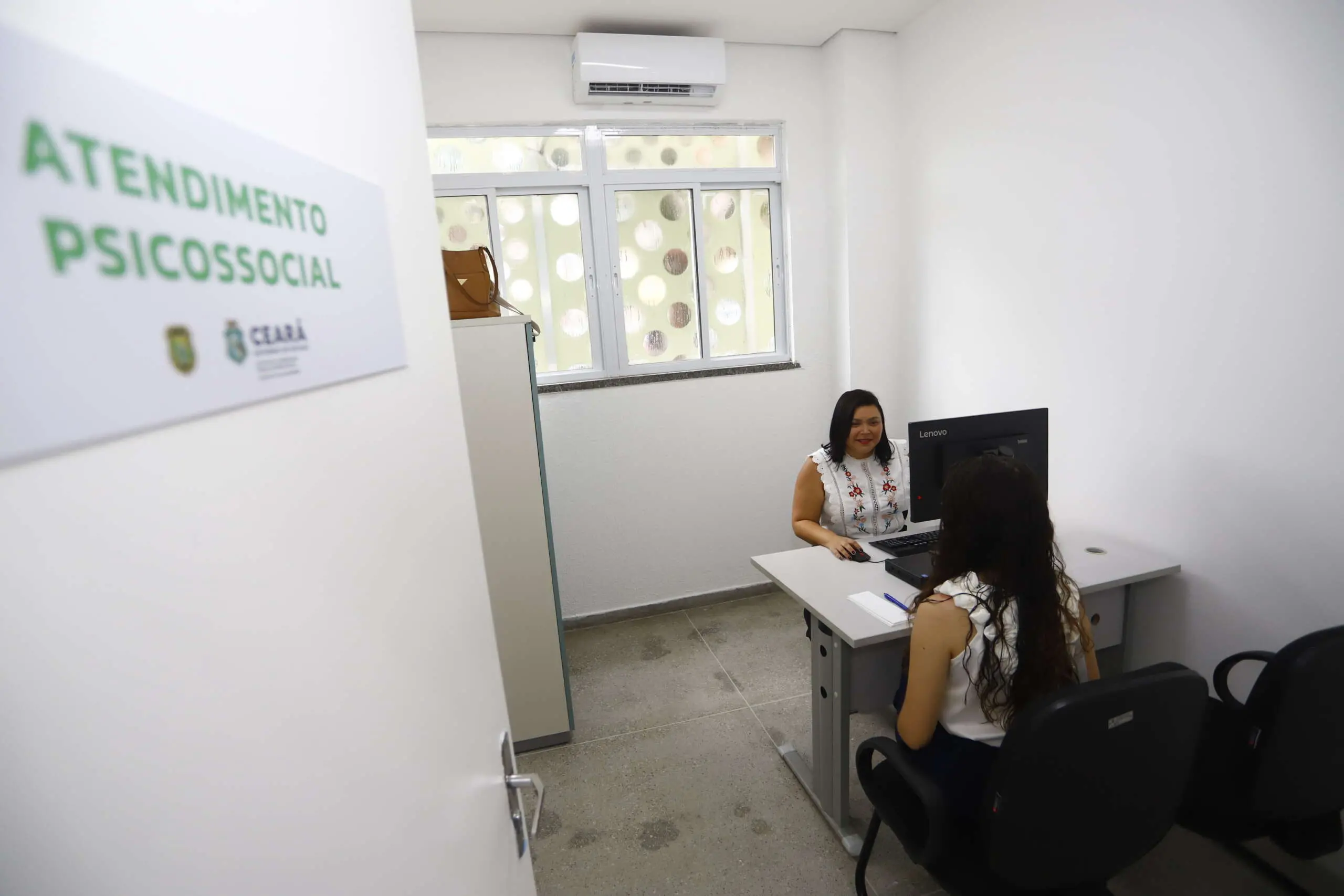Imagem de um atendimento psicossocial em ambiente acolhedor, com duas mulheres conversando em um escritório bem iluminado.