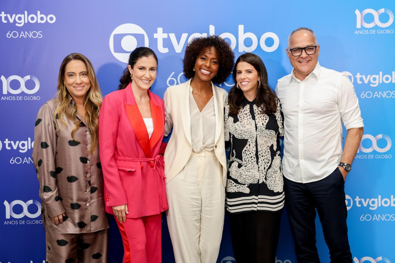 Mnica Almeida, diretora de gênero, Leonora Bardini, diretora executiva da TV Globo, Maju Coutinho, Antonia Prado, diretora artística do Show 60 anos e Amauri Soares, diretor dos Estúdios Globo, TV Globo e Afiliadas sobre fundo azul com símbolo e palavra TV Glogo
