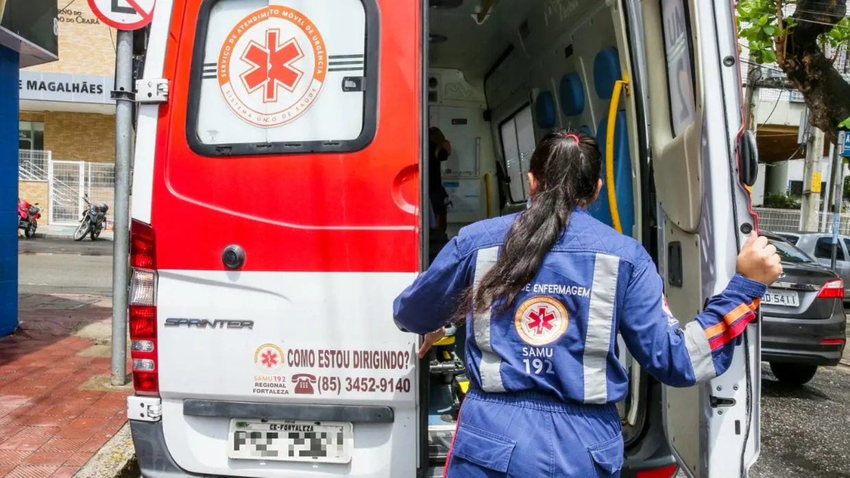 Imagem de mulher vestida de profissional da saúde e abrindo a porta de uma ambulância