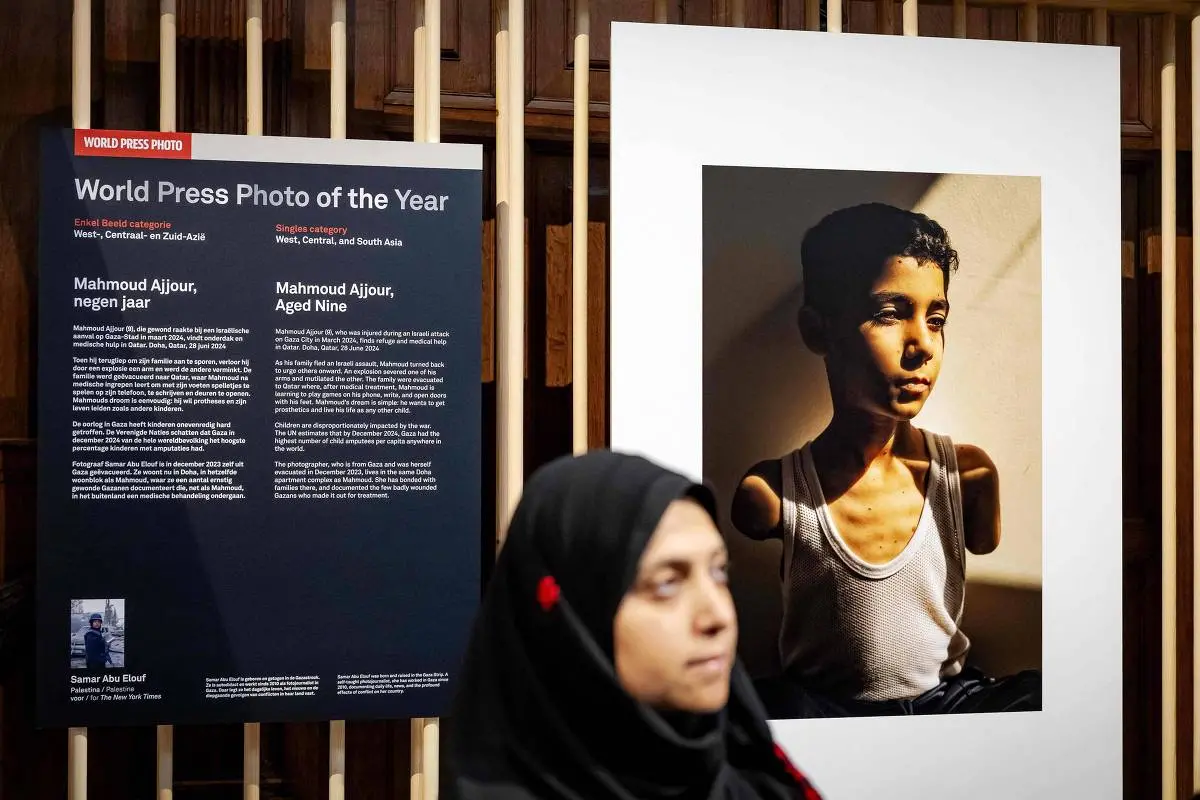 Fotógrafa Samar Abu Elouf em frente ao retrato premiado como 