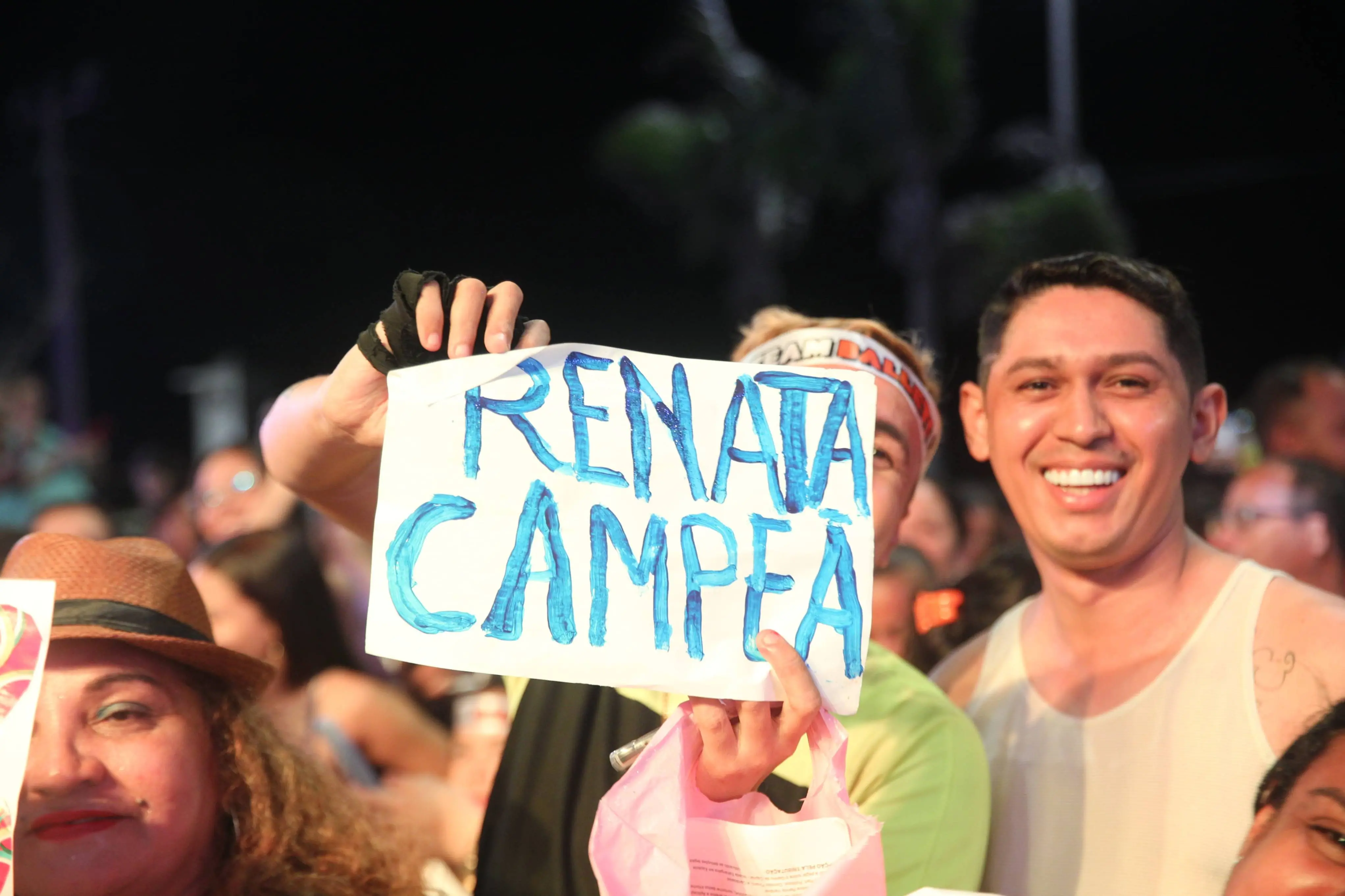 Imagem de dois fãs de Renata no Estoril, na Praia de Iracema, segurando um cartaz