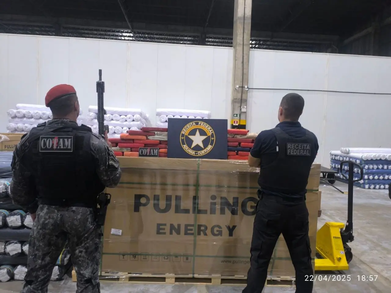 dois policiais de costas diante de carga de cocaína apreendida em fortaleza