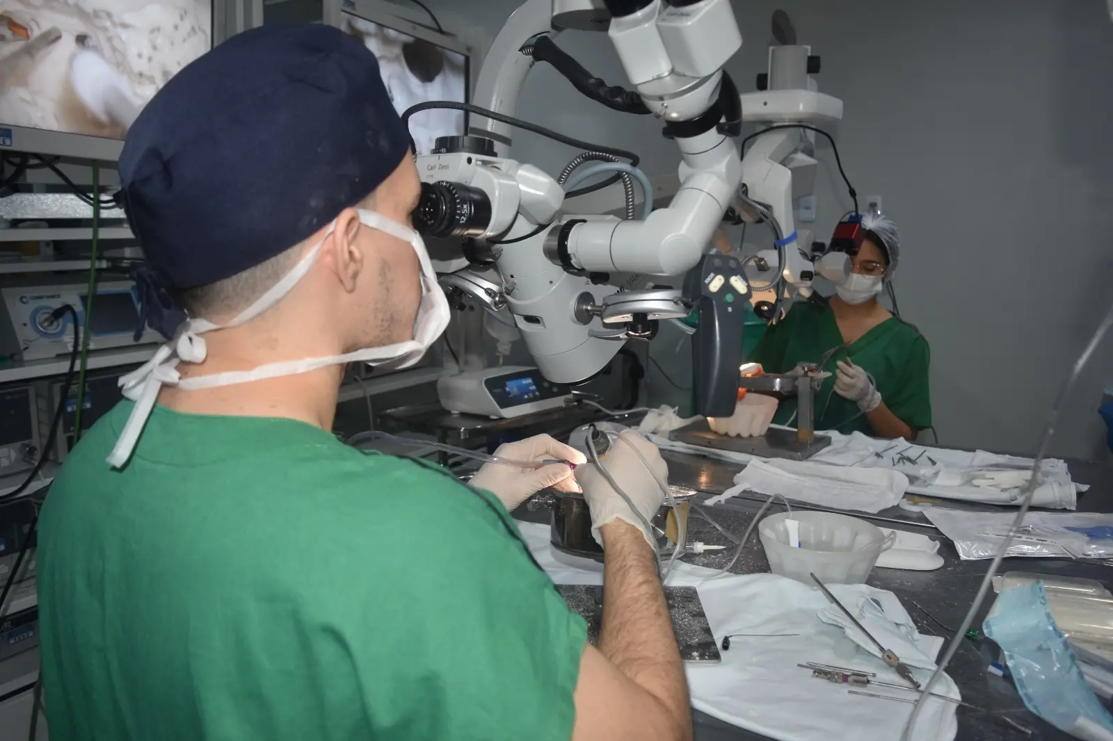 Profissional de saúde olha no microscópio durante treino de cirurgia