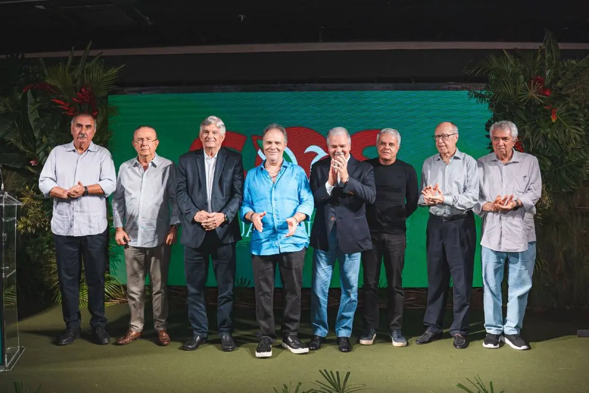 Na imagem, os oito homens que compõem a diretoria do SOS Guaramiranga aparcem ao lado um do outro. São todos homens brancos e grisalhos, que estão no palco de um evento.