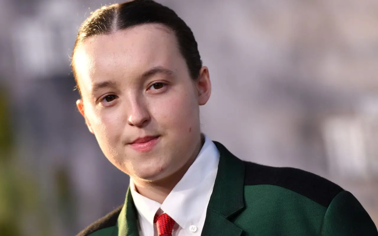 Bella Ramsey, de lado, usando terno verde