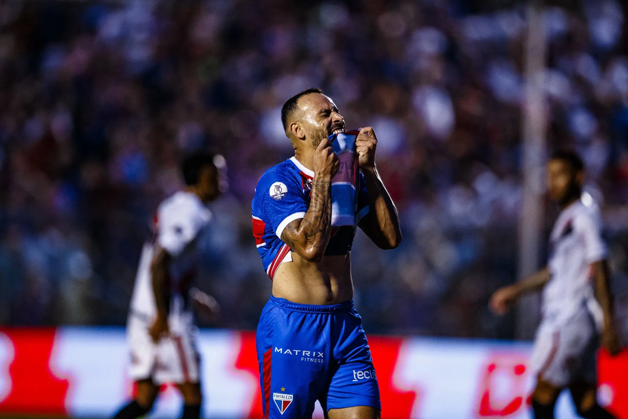 Foto de Moisés, atacante do Fortaleza, lamentando e mordendo a camisa.
