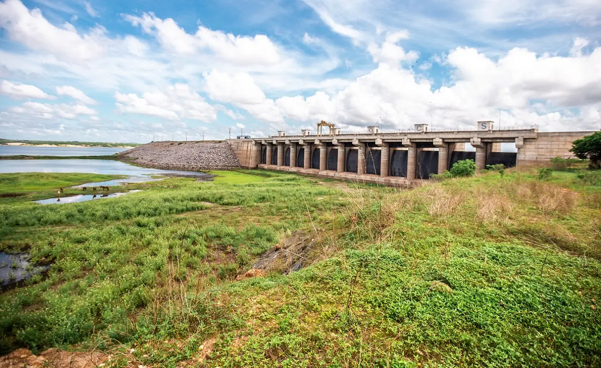 Foto do açude Castanhão em fevereiro de 2025, com água, áreas verdes e as comportas fechadas