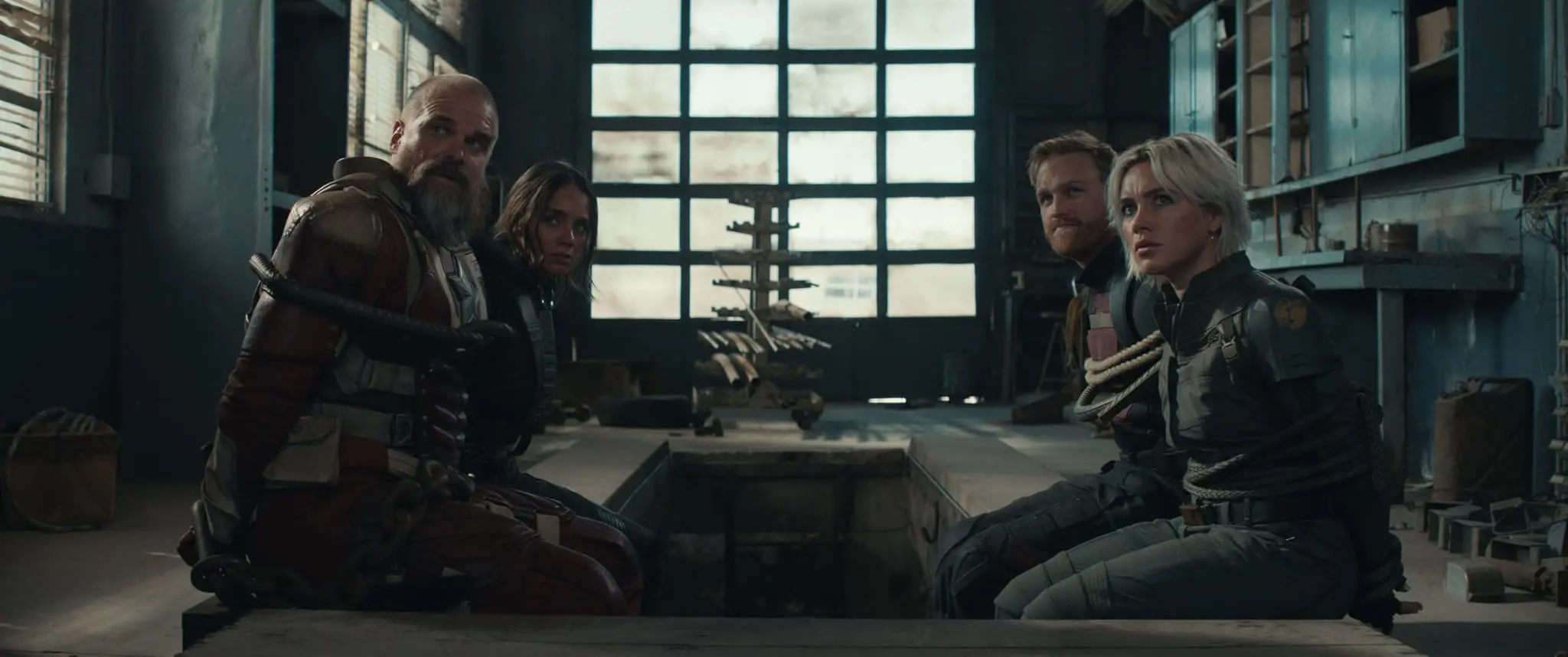 Imagem dos personagens do filme Thunderbolts presos e sentados em ambiente com pouca iluminação