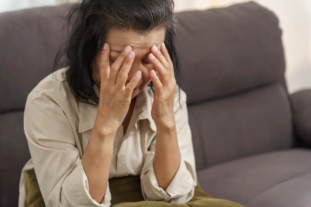 Imagem mostra mulher de meio-idade segurando o rosto com expressão de angústia, ilustrando saúde mental na menopausa e risco de depressão, ansiedade e Alzheimer