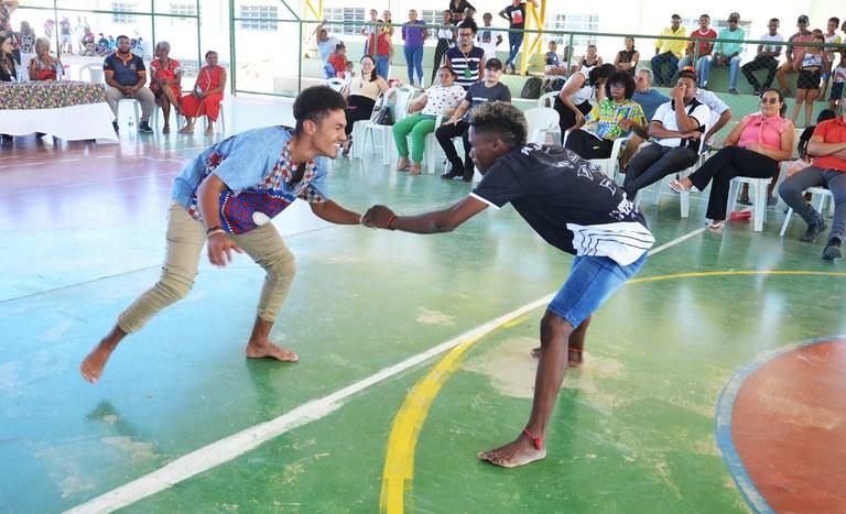 Dois jovens quilombolas praticam capoeira em quadra de escola durante evento de entrega de títulos de terra