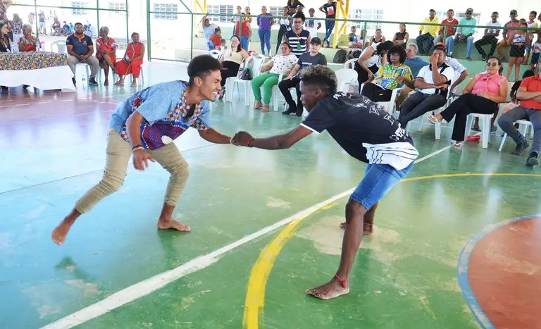 Dois jovens quilombolas praticam capoeira em quadra de escola durante evento de entrega de títulos de terra