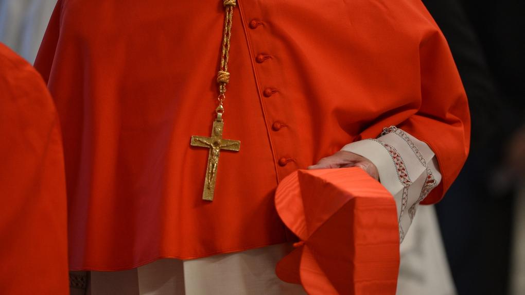 Imagem foca em mãos e vestes de cardeal em conclave, ilustrando início do rito para escolha de novo papa no vaticano
