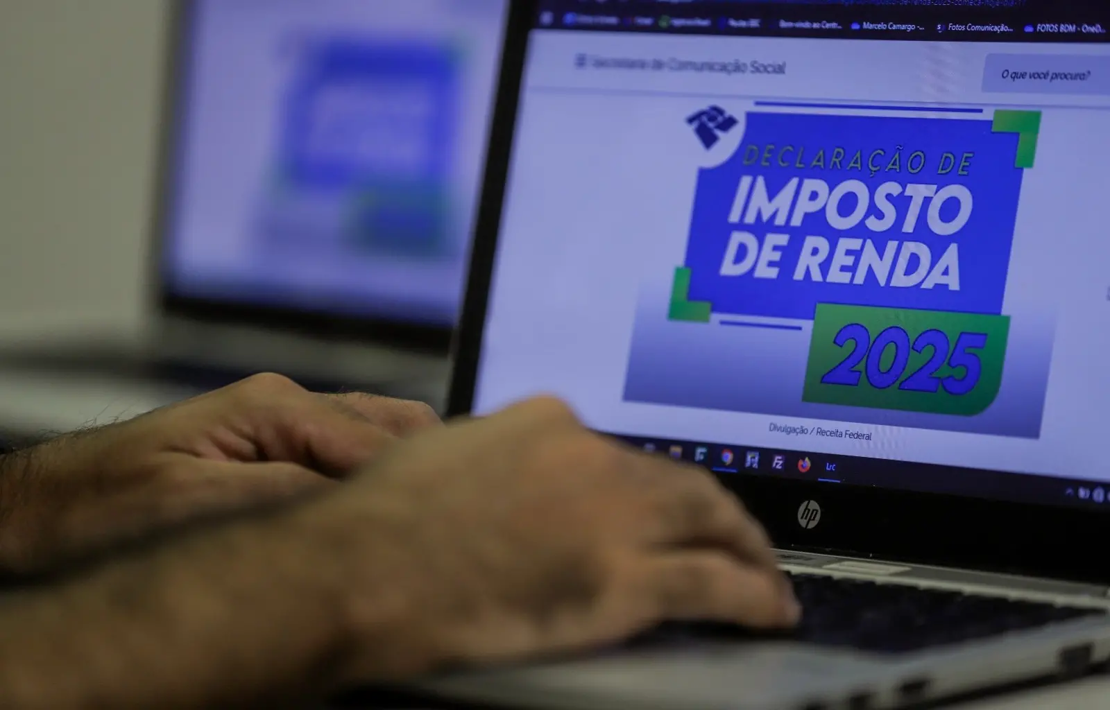 Mão digita em notebook aberto no site do Imposto de Renda