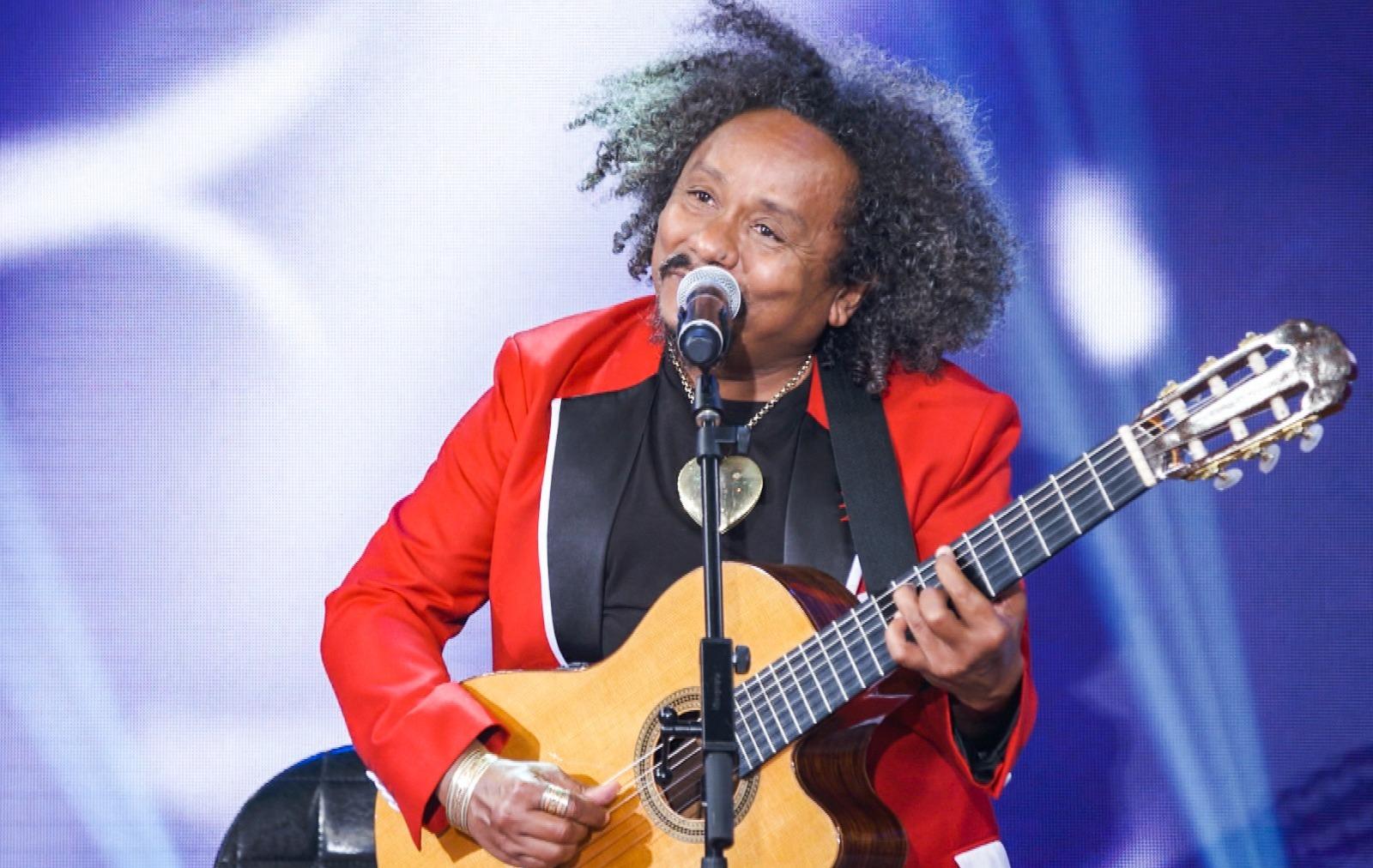 Chico César segura violão enquanto se apresenta