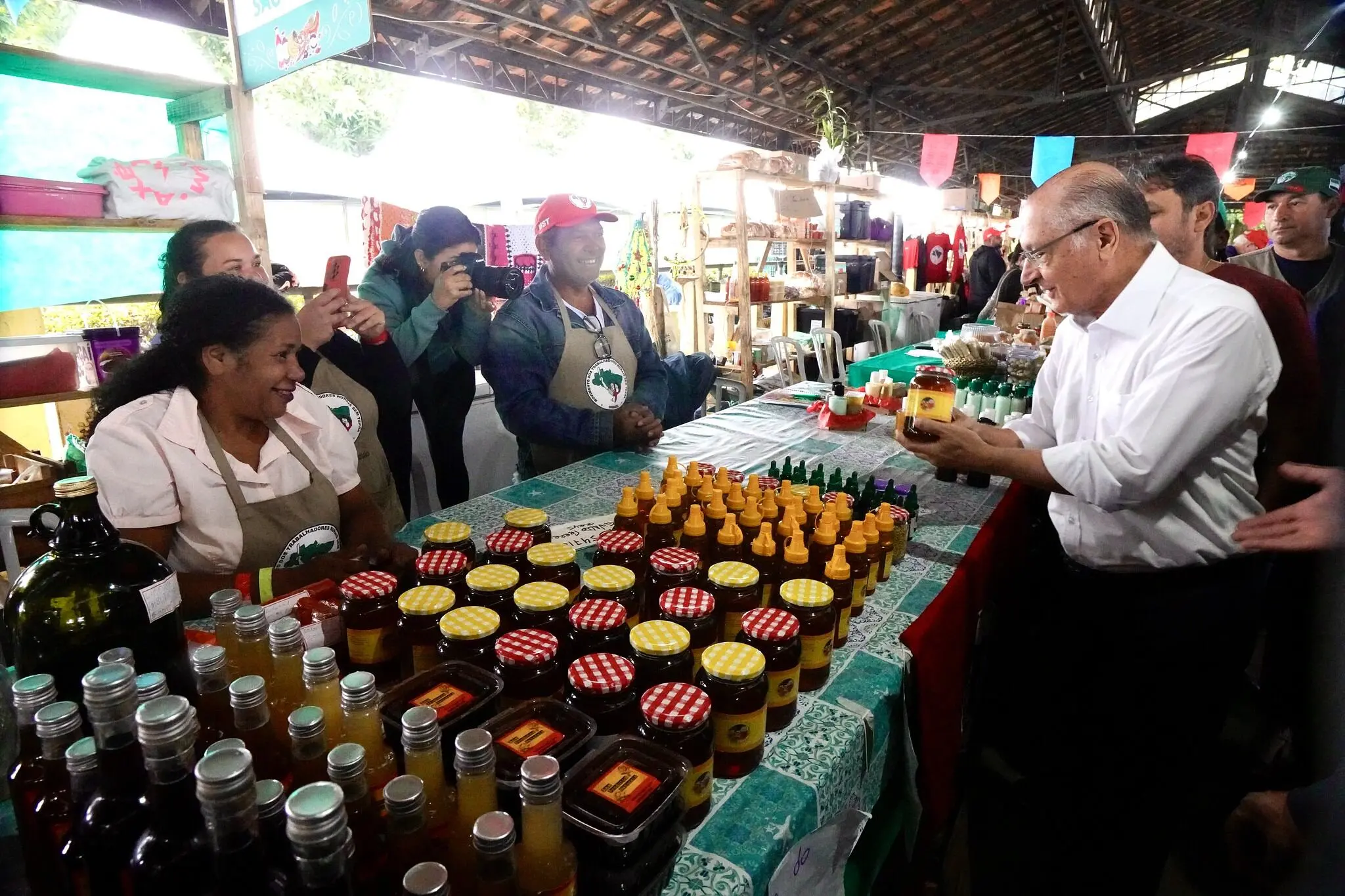 Geraldo Alckmin, presidente em exercício, segura item de uma das expositoras da 5ª Feira Nacional da Reforma Agrária e conversa com produtoras rurais