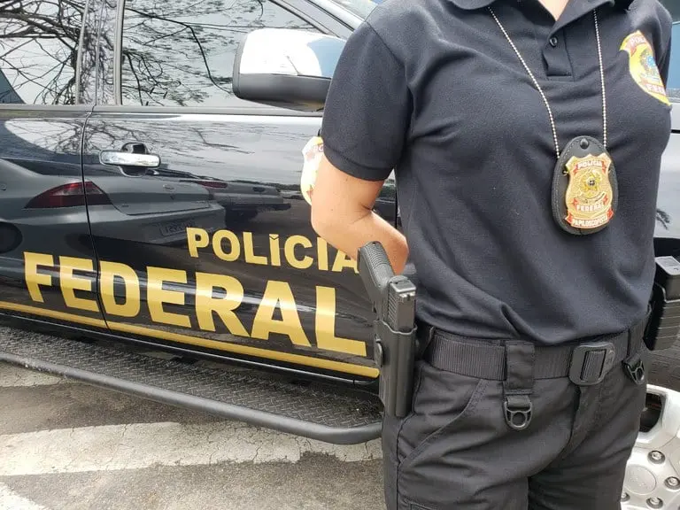 Imagem de um agente da polícia federal em frente a um veículo oficial, destacando a atuação e a segurança da força policial.