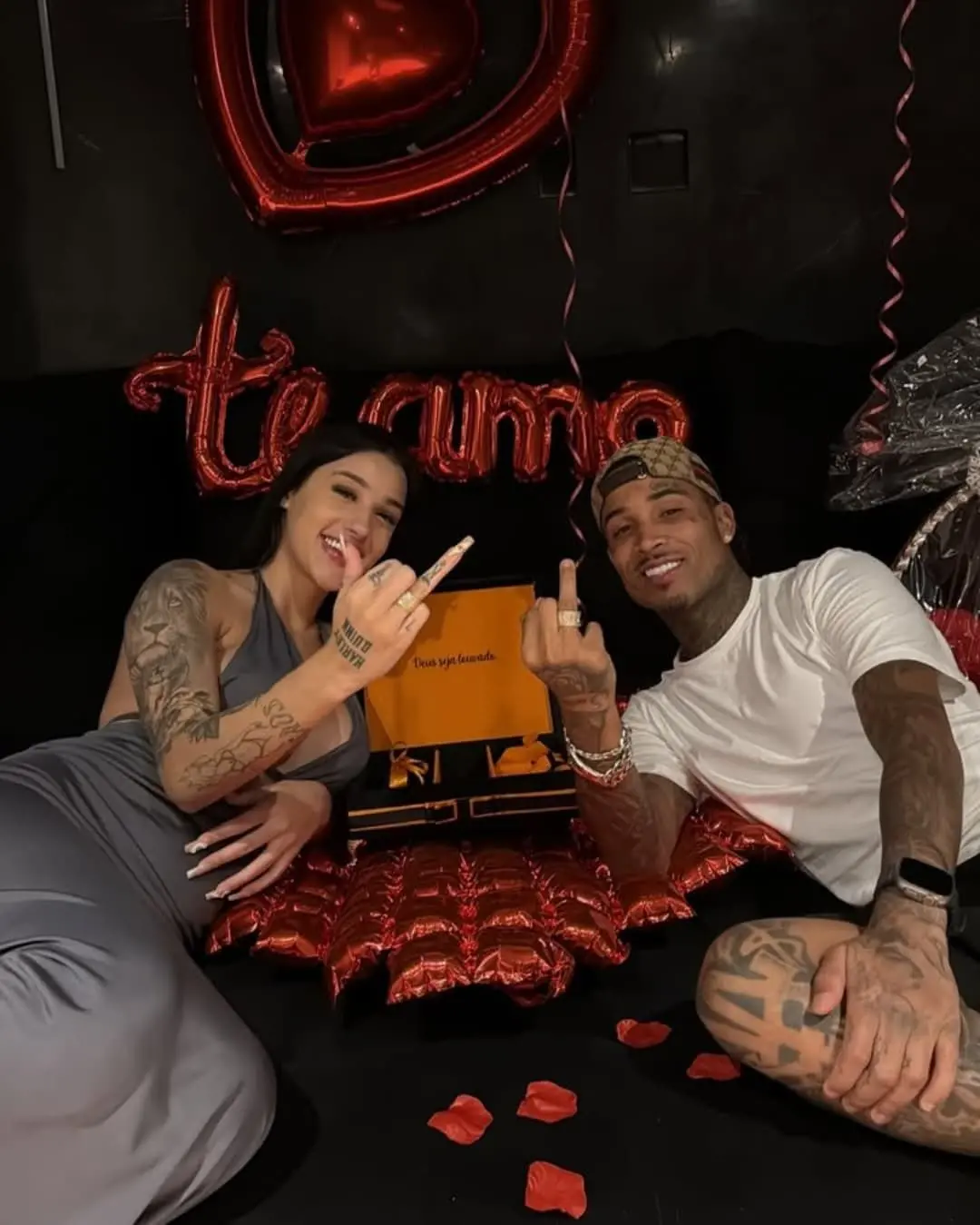 Bia Miranda e Gato Preto mostram alianças no dedo, diante de painel escrito te amo