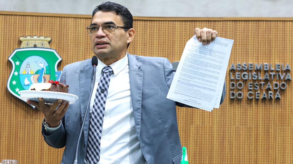Reginauro segurando bolo durante discurso na tribuna da Alece