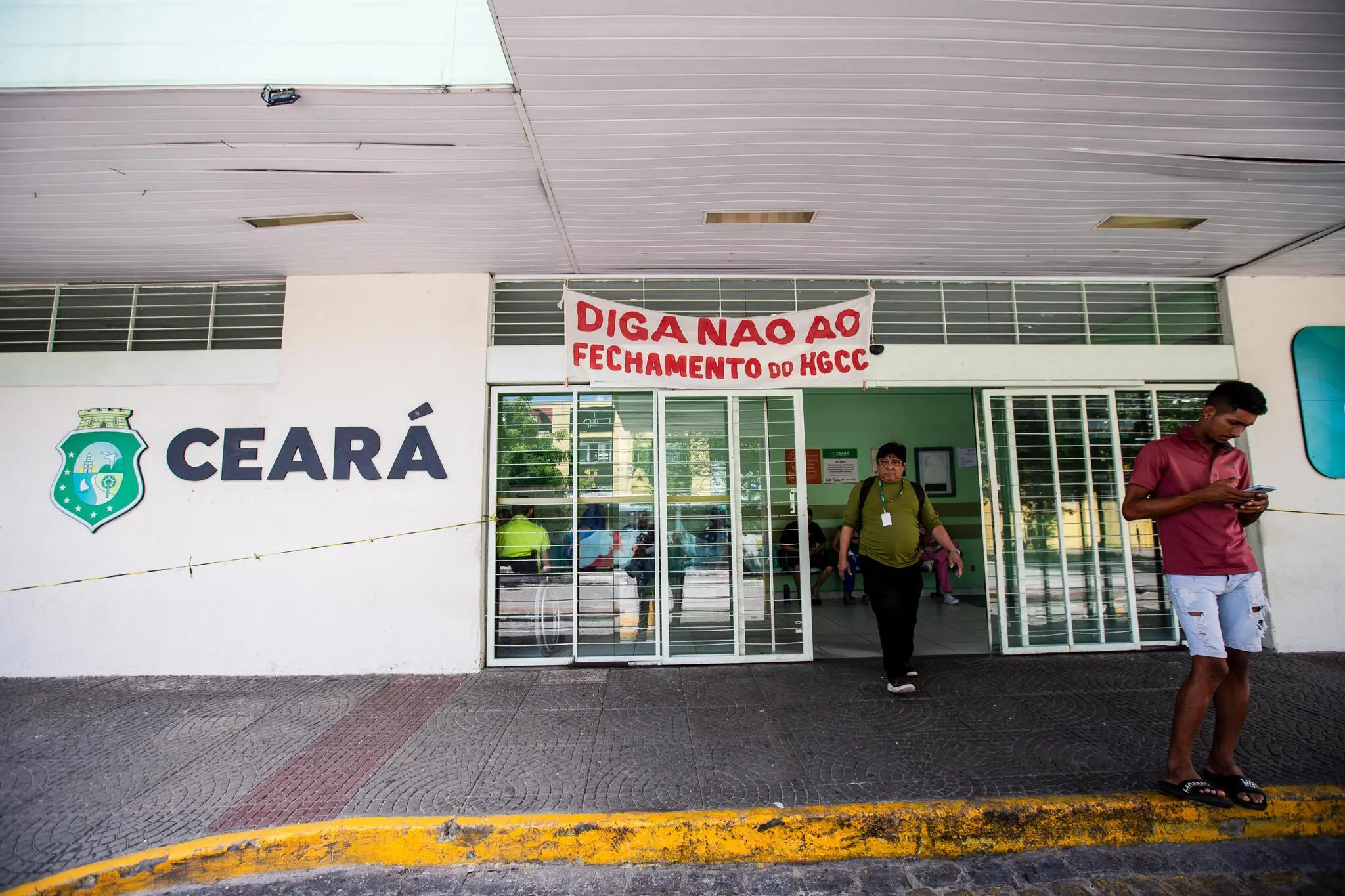 Fachada do Hospital César Cals, com pessoas saindo do local e faixa com frase 