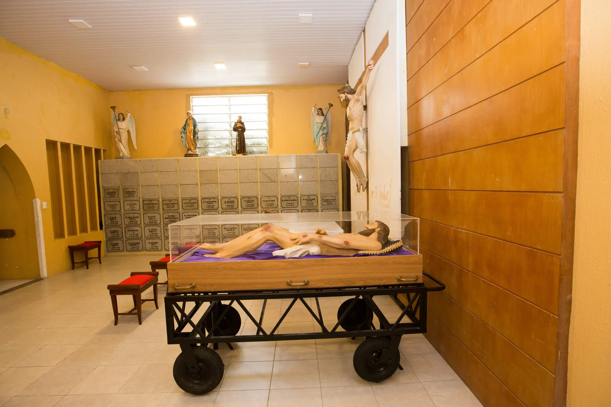 Ossuário da Igreja Cristo Rei, com os restos mortais de padres jesuítas ao fundo e uma imagem de Jesus deitado, à frente