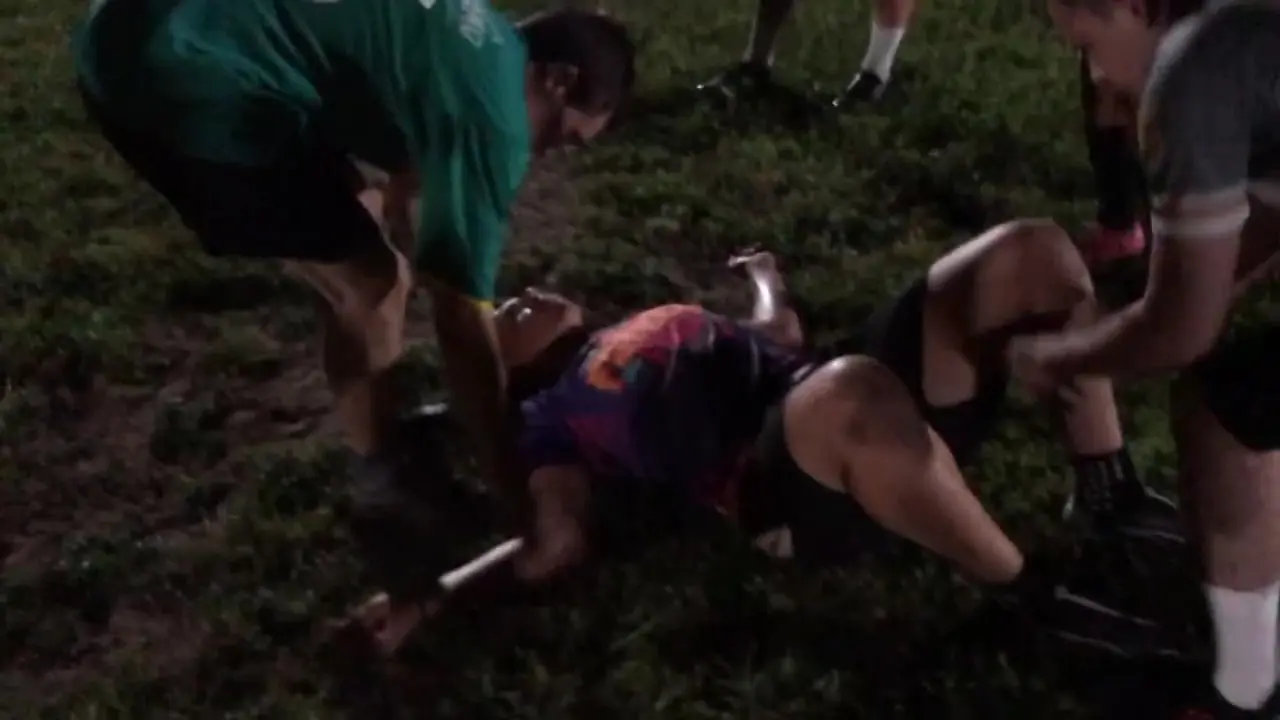 Imagem que mostra um jogador caído no chão durante uma partida de futebol, sendo ajudado por outros jogadores em campo. Imagem é para matéria informando sobre fio que se rompeu e atletas sofreram com choque elétrico