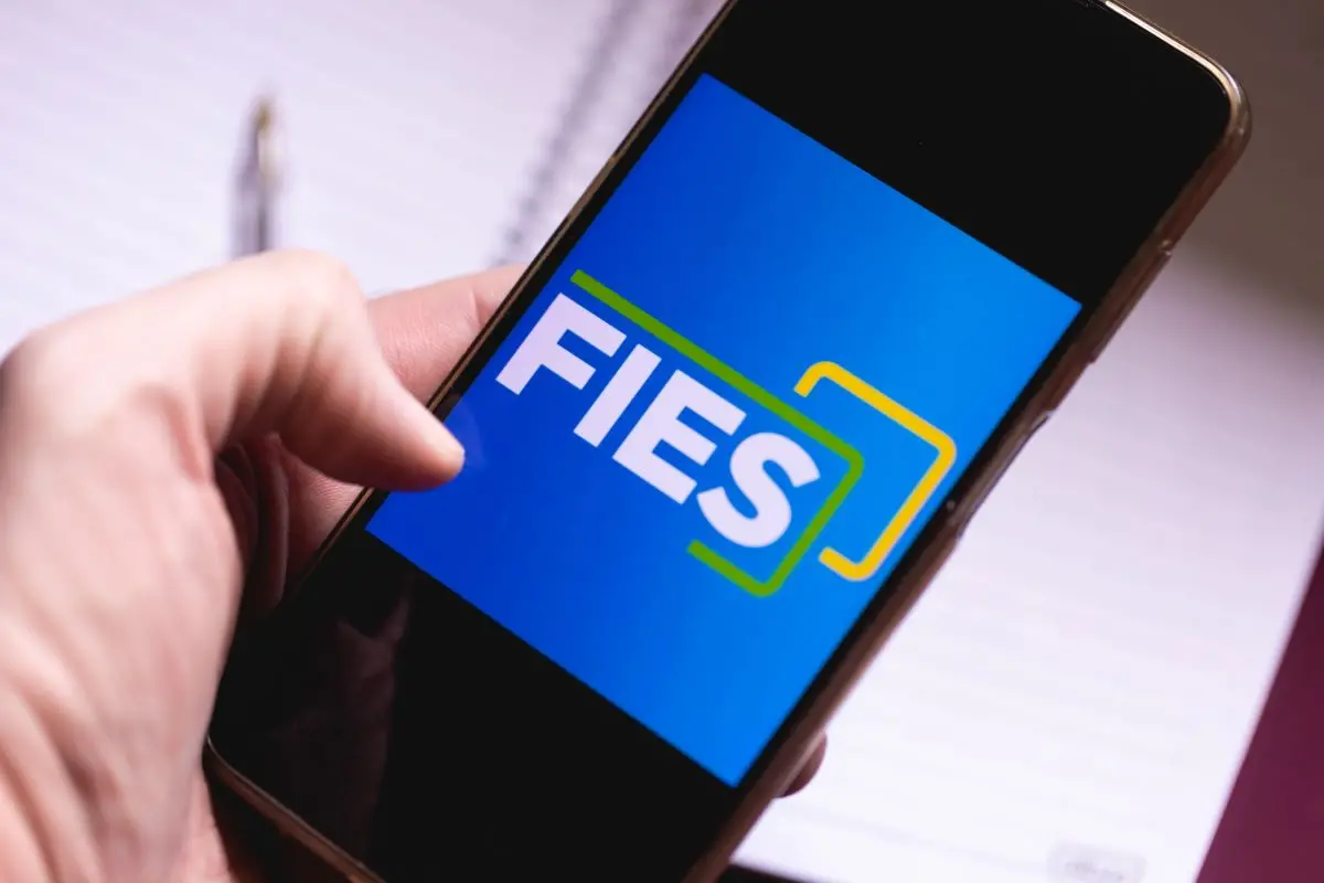 Foto de pessoa mexendo em celular com logomarca do Fies