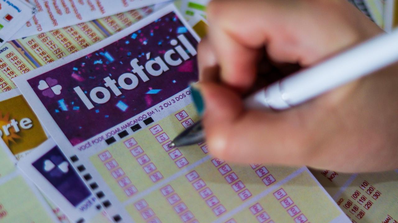 Imagem mostra mão segurando canenta enquanto preenche jogo da lotofácil, ilustrando bolão que venceu a lotofácil 3395 no Tocantins