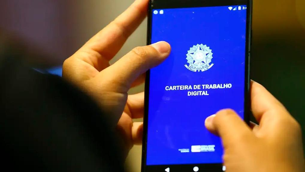 Mãos segurando celular com aplicativo Carteira de Trabalho Digital aberto