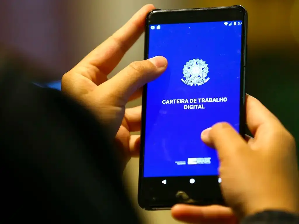 Mãos segurando celular com aplicativo Carteira de Trabalho Digital aberto