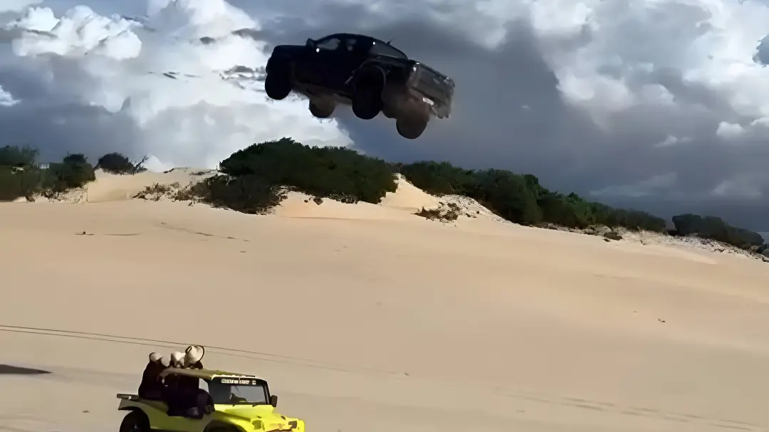 Foto que contém um carro que voa ao subir duna de Canoa Quebrada em alta velocidade, logo abaixo tem um buggy amarelo com turista dentro