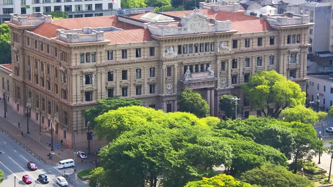 Fachada impressionante de um edifício histórico, destacando detalhes arquitetônicos e a vegetação ao redor, sob um céu azul-claro para matéria sobre juiz que usou nome falso por 40 anos