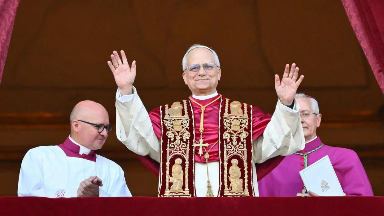 imagem mostra o papa Leão XIV com veste tracidionais em uma sacada e com as mãos erguida em uma espécie de benção