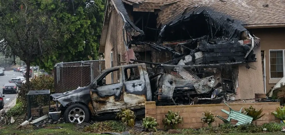 Casa atingida pelo avião, com carro totalmente incendiado