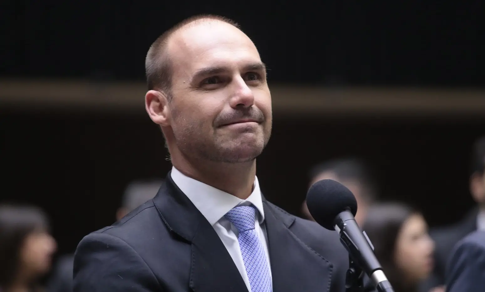 Eduardo Bolsonaro é um homem branco, calvo e de barba rala. Na foto, está de terno preto, camisa social branca e gravata azul. Para matéria sobre PGR pedir abertura de inquérito para investigar o filho de Bolsonaro sobre atuação nos EUA contra autoridades brasileiras