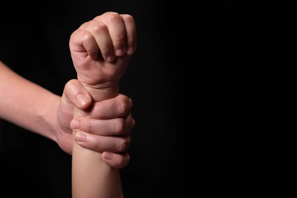 Mão de adulto segura braço de criança