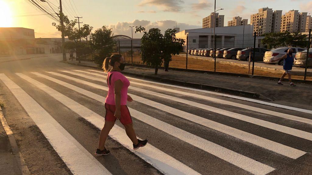 foto da avenida Lineu Machado, em Fortaleza. Na imagem, uma mulher atravessa a faixa de pedestres