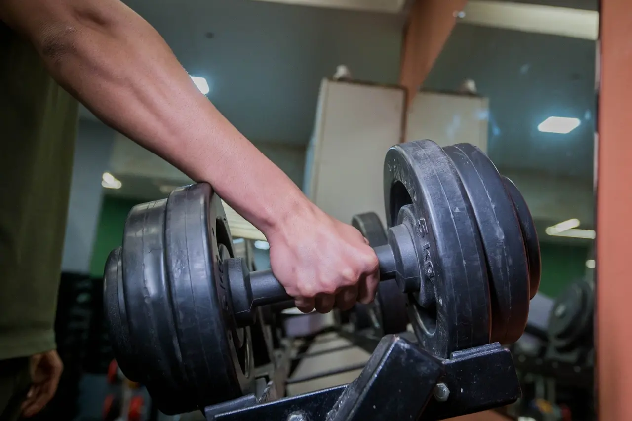 Imagem mostra uma mão manuseando um halter em uma academia de Fortaleza para matéria sobre apps de bem-estar