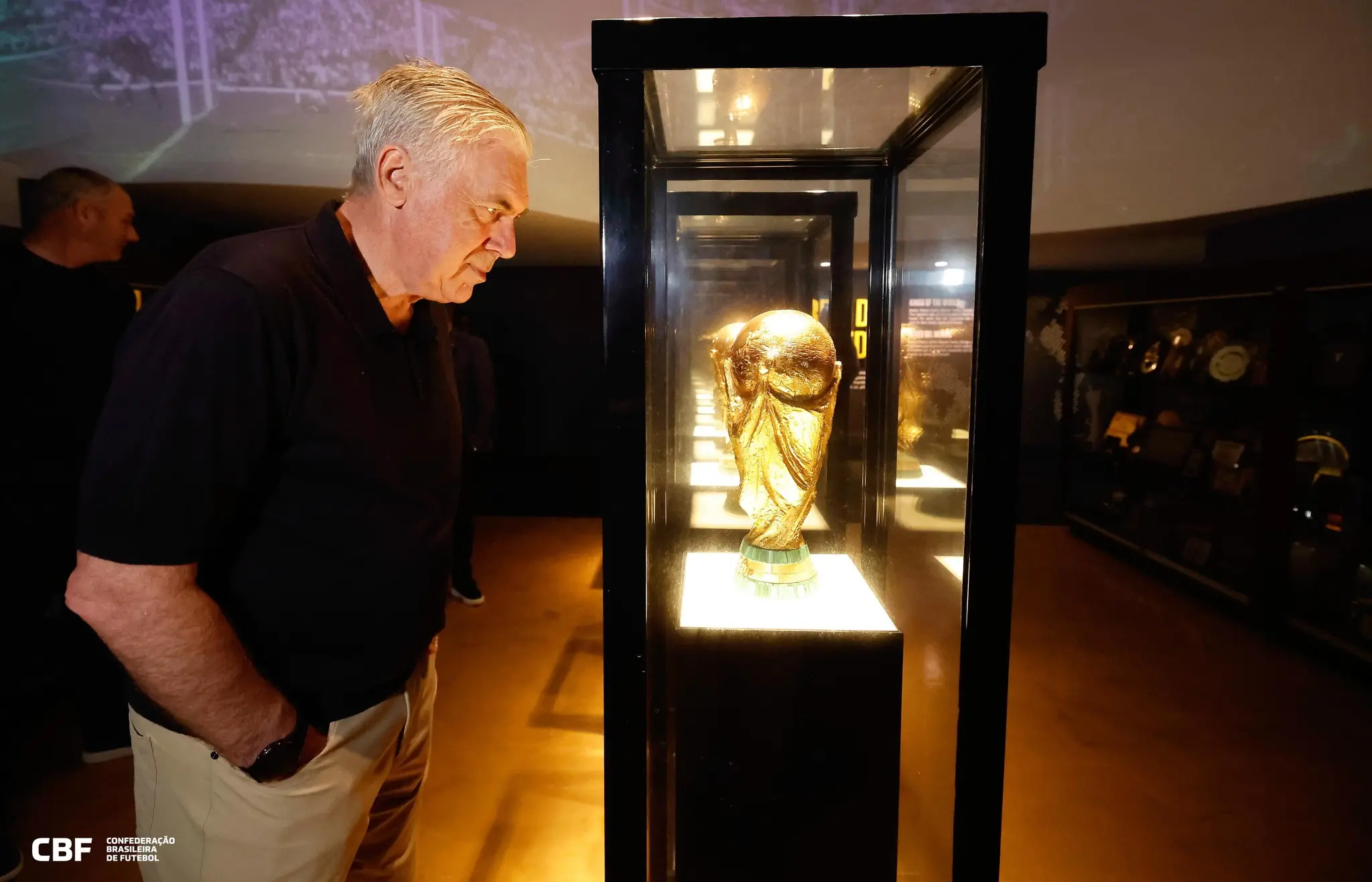 Foto de Carlo Ancelotti, treinador a Seleção Brasileira, olhando para taça da Copa do Mundo.