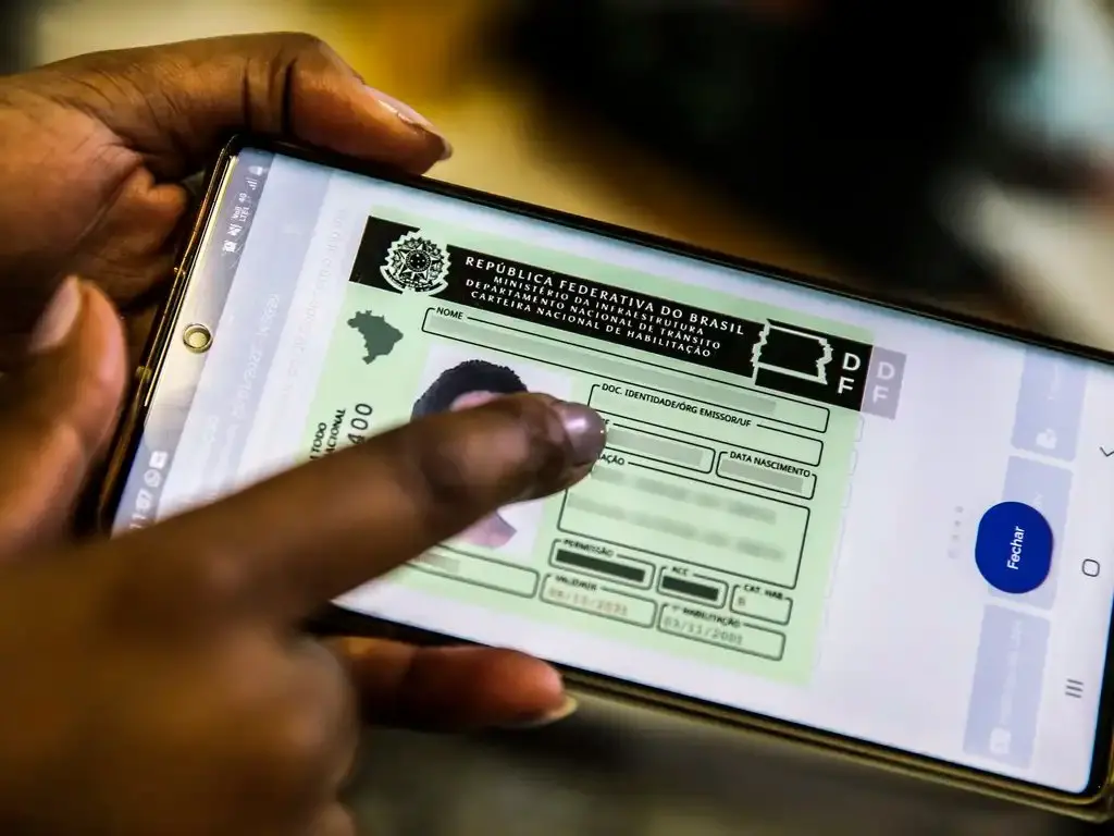 Mão mostra CNH digital em aplicativo no celular