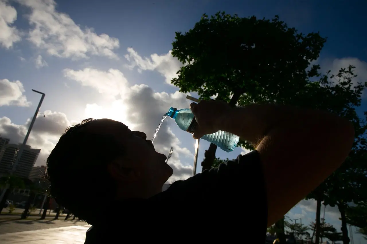 pessoa jogando água na boca, em cena contraluz