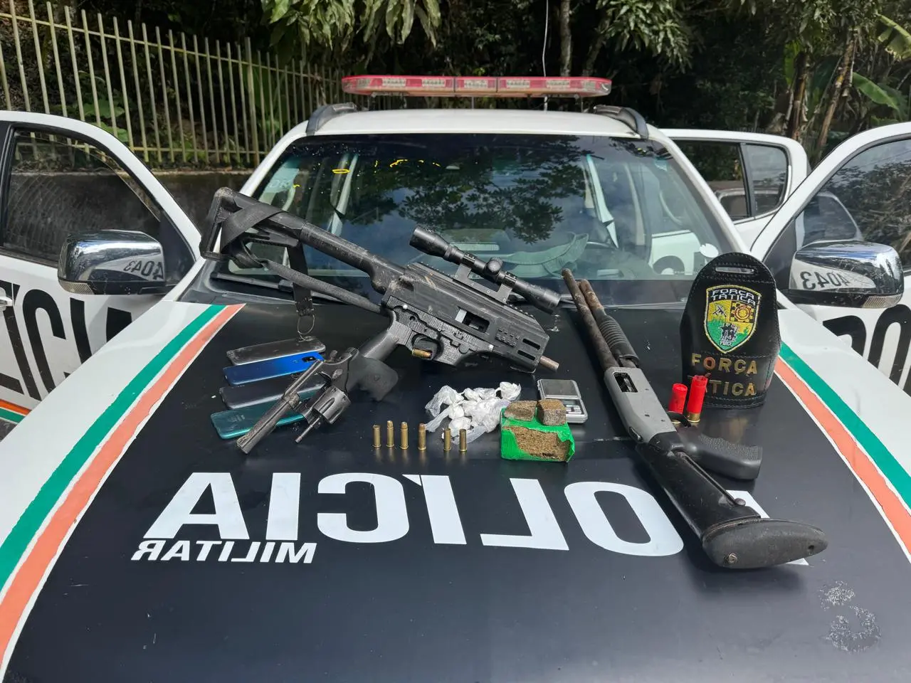 Foto de material apreendido pela Polícia Militar em confronto com criminosos em Aratuba, no Interior do Ceará. Na imagem, armas de fogo, munições e drogas em cima da viatura policial